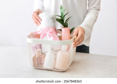 Woman Holding Gift Basket With Cosmetics On Light Background