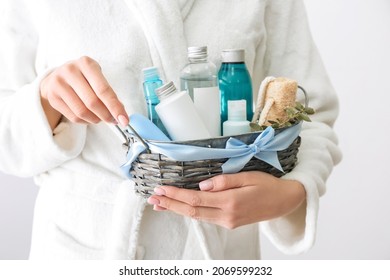 Woman Holding Gift Basket With Cosmetics On Light Background, Closeup