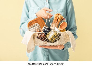 Woman Holding Gift Basket With Products On Color Background