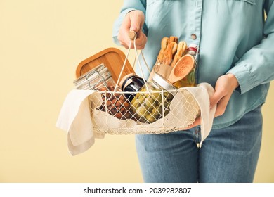 Woman Holding Gift Basket With Products On Color Background