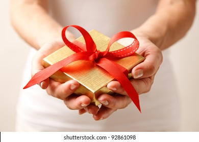 Woman Holding A Gift Box In A Gesture Of Giving.