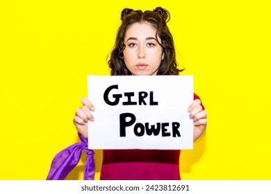 Woman holding a "Girl Power" sign directly in front of her, exuding confidence and advocating for female empowerment against a vivid yellow backdrop. - Powered by Shutterstock