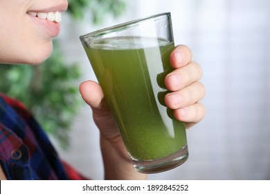 Woman Holding Glass With Fresh Celery Juice Indoors, Closeup