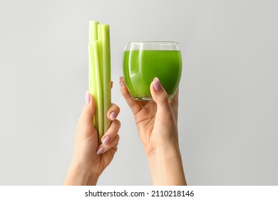 Woman Holding Glass Of Green Juice And Celery On Light Background