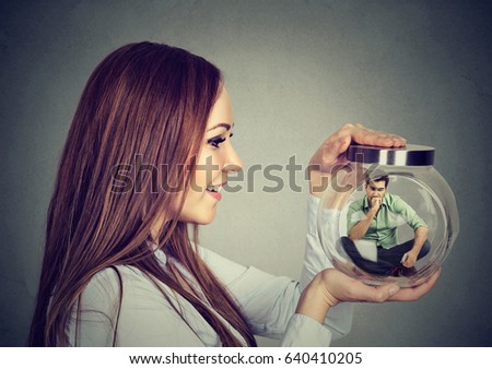 Woman holding a glass jar with imprisoned man in it