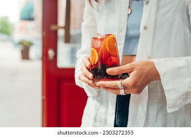 Woman holding glass with refreshing fruit sangria