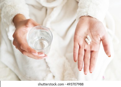 Woman holding a glass of water and pills, detail  