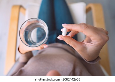 Woman Holding Glass Of Water And Taking Pill, Medicine, Antidepressant Or Antibiotic. Painkiller From Headache Or Stomach Pain