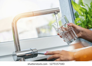 Woman Holding Glass At Water Tap And Filling Water