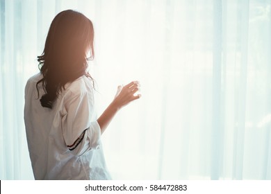 Woman Holding A Glass Of Water While Looking Out Of The Window - Back Of Silhouette Woman