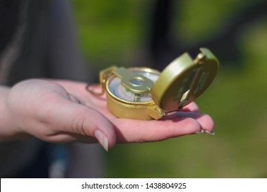 Woman Holding A Golden Compass In Her Hand During The Day.