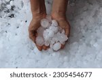 Woman holding golf ball sized hail after a hailstorm in North Texas