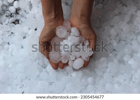 Woman holding golf ball sized hail after a hailstorm in North Texas