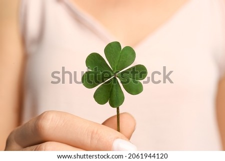 Woman holding green four leaf clover in hand, closeup