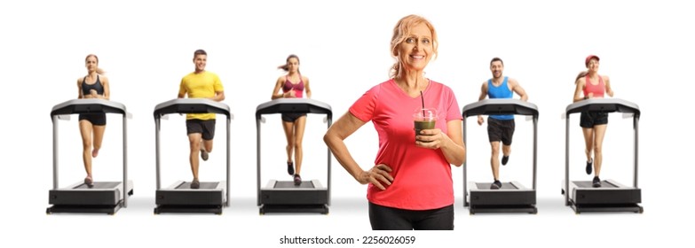 Woman holding a green healthy smoothie in front of people running on treadmills isolated on white background - Shutterstock ID 2256026059