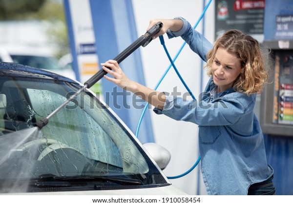 woman holding green\
nozzle at gas station