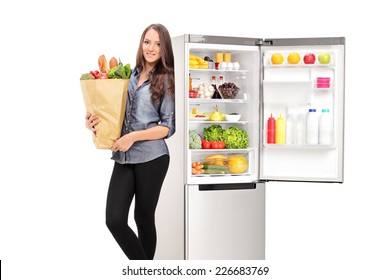 Woman holding a grocery bag by an open fridge isolated on white background