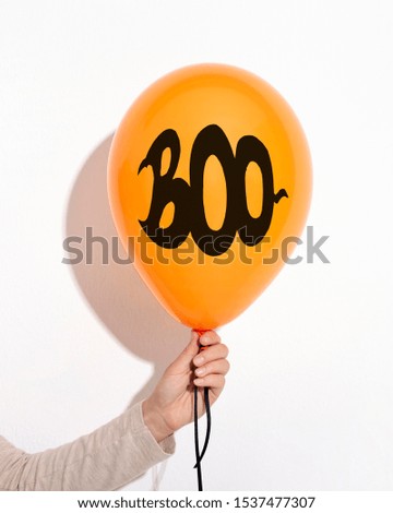 Woman holding Halloween balloon with boo creative text over white background