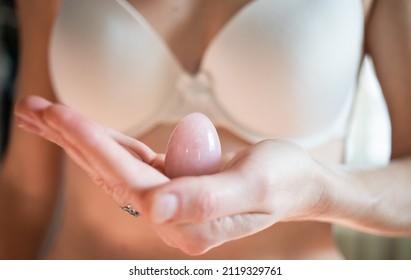 Woman Holding In Hand A Vaginal (yoni) Egg. Rose Quartz Crystal Egg.