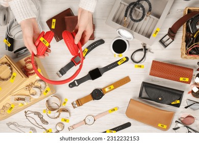 Woman holding headphones near table with different stuff, top view. Garage sale - Shutterstock ID 2312232153
