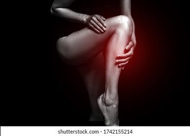 Woman Holding Her Beautiful Healthy Leg With Massaging Knee And Calf In Pain Area Black And White Color With Red Highlighted. Dark Background. Studio. Legs Woman. Female. Photo. Life. 