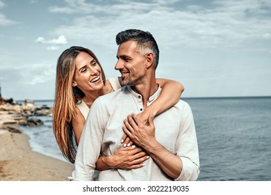 Woman holding her husband from behind standing at a beach on a sunny day. Romantic couple on standing near the sea together. - Powered by Shutterstock