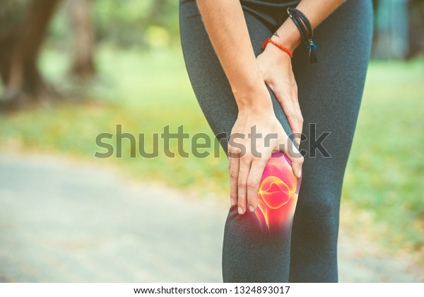 Woman\
holding her knee with red pain on the\
skeleton