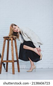 A Woman Is Holding Her Leg She Is Wearing High Heeled Shoes And Her Legs Hurt. The Woman Is Wearing A Black Dress And Beige High Heel Shoes. Leg Pain From High Heels