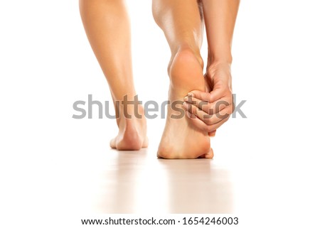 woman holding her painful foot on white background
