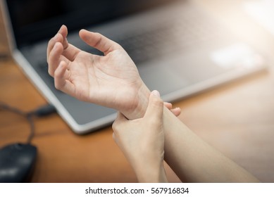 Woman holding her wrist pain from using computer. Office syndrome 