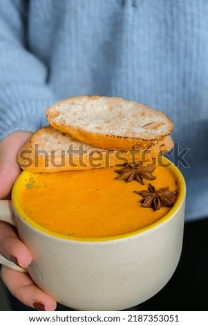 Woman holding Homemade carrot ginger curcuma spicy soup. Seasonal Pumpkin traditional soup with creamy silky texture. Healthy vegan clean eating. Prevention of antiviral infections