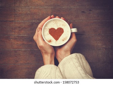 woman holding hot cup of coffee, with heart shape
