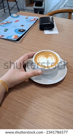 Woman holding a hot cup of coffee with a heart shape
