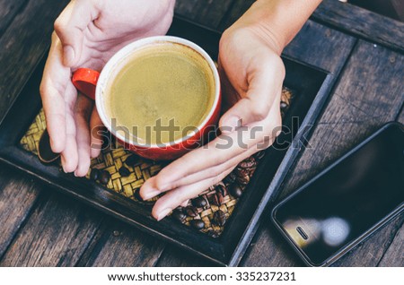 woman holding hot cup of coffee,on table wooden in thailand