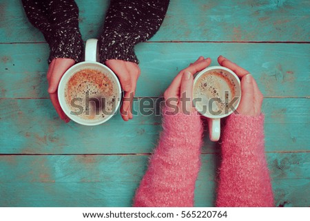 woman holding hot cup of tea on wooden background.