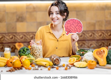 Woman Holding Human Brain Model With Variety Of Healthy Fresh Food On The Table. Concept Of Balanced Nutrition For Brain Health