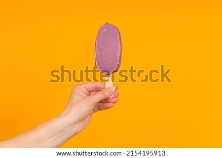 woman holding ice cream on a stick in her hand, colored background