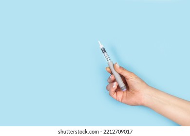 Woman Holding An Insulin Injection Pen On A Light Blue Background With Copy Space