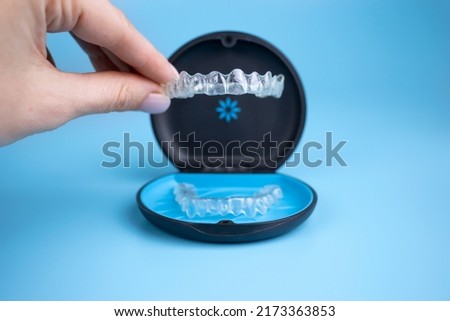 Woman holding invisalign transparent retainers with a box on the table, flatlay top view. Selective focus.
