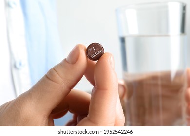 Woman Holding Iodine Pill And Glass Of Water, Closeup