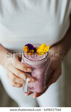 Mann hält einen Milchshake aus Beeren und Haferflocken.