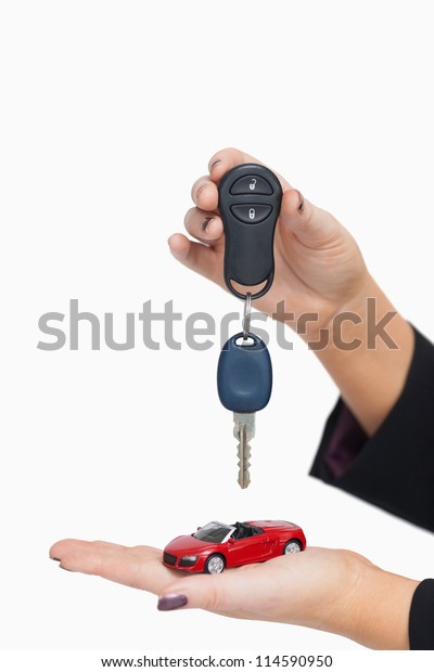 Woman\
holding key and small car against white\
background