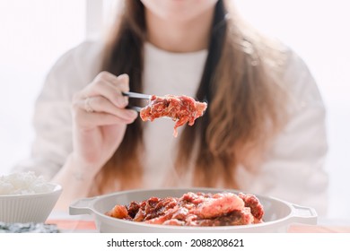 A Woman Holding Korean Food Jjimgalbi With Chopsticks.