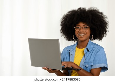 Woman holding a laptop and typing on the keyboard, looking at the camera, black woman on white background - Powered by Shutterstock