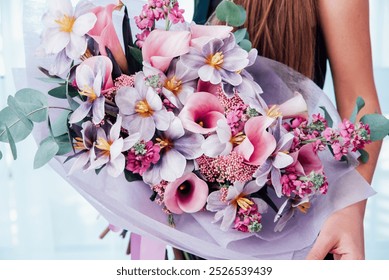 Woman holding large bouquet of flowers wrapped in purple paper. bouquet in shades of pink, purple and white lilies, tulips and other small flowers. floral card. Mothers day, International Women's Day - Powered by Shutterstock