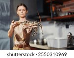 Woman holding a large lobster in a kitchen setting for stock photo