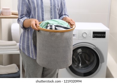 Woman Holding Laundry Basket With Dirty Clothes In Bathroom