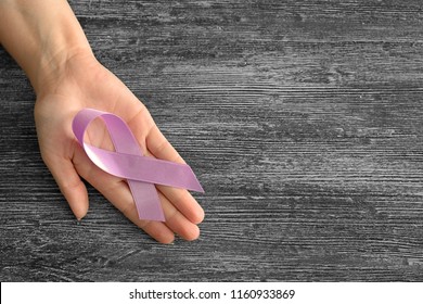 Woman holding lavender ribbon on wooden background. Cancer awareness concept - Shutterstock ID 1160933869