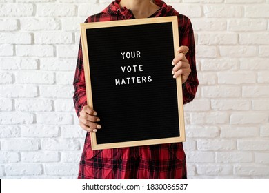 Woman Holding Letter Board With Text Your Vote Matters On White Brick Background