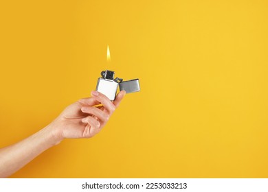 Woman holding lighter with burning flame on orange background, closeup. Space for text - Powered by Shutterstock